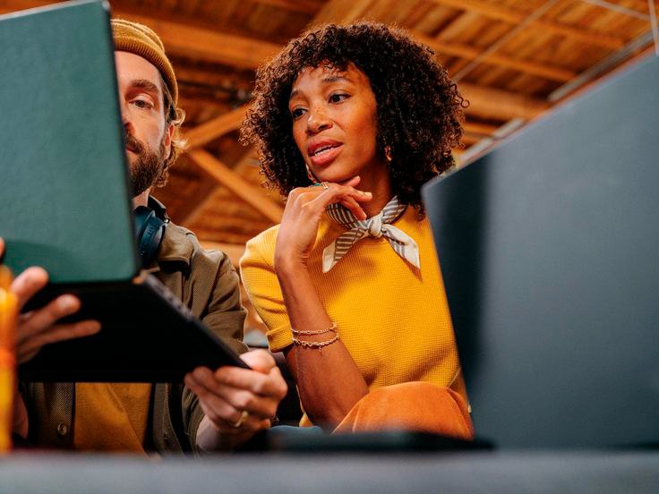 Dupla de profissionais de marketing analisando dados juntos em um notebook